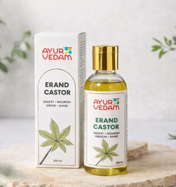 A bottle of Cold Pressed Erand Castor Oil by Ayurvedam 100ml placed on a wooden table,with few castor leaves in the background