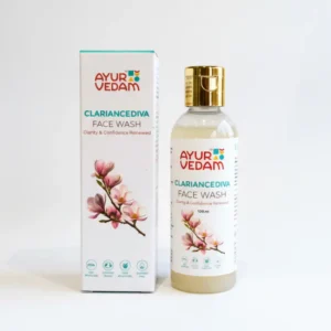 A 100ml bottle and cardboard box of Ayurvedam Clariance Diva Face Wash. The packaging is white with a gold flip-top cap and features a delicate illustration of pink magnolia blossoms. The label includes the tagline "Clarity & Confidence Renewed" along with icons for FDA approval and sulfate-free formula.
