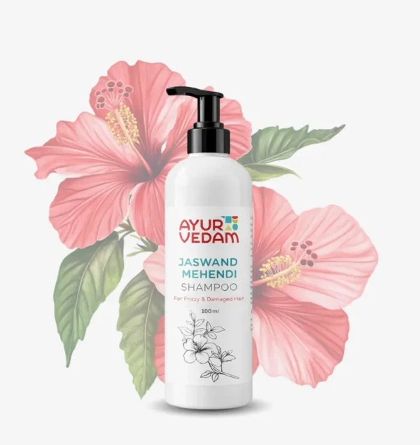 A 100ml white pump bottle of Ayurvedam Jaswand Mehendi Shampoo for frizzy and damaged hair, displayed against a background of large pink hibiscus flowers.