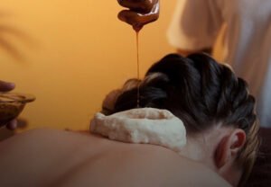 A woman enjoying a Manya Basti treatment at ayurvedam store, receiving professional care with calming oil on her neck.