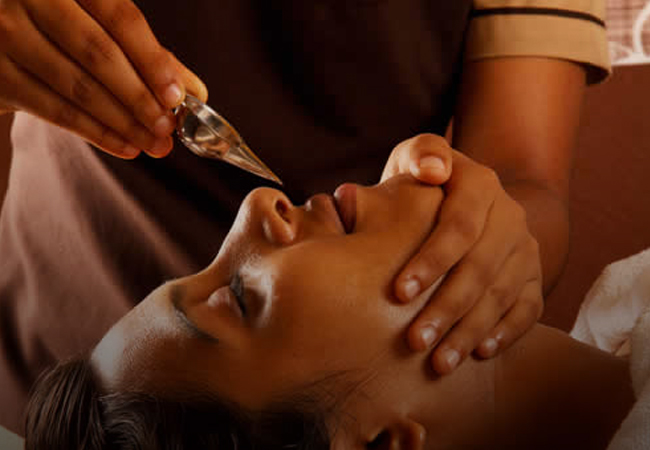 A woman enjoying a nassyam treatment at ayurvedam store, receiving professional care for her skin's rejuvenation and relaxation.