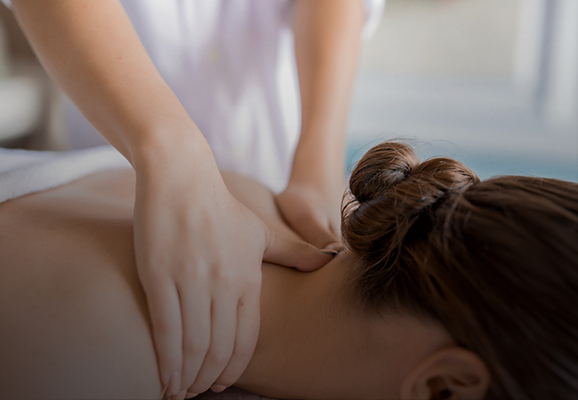 A person is getting a relaxing shoulder and neck massage at Ayurvedam Store. The masseuse’s hands are gently pressing on the person’s shoulders.