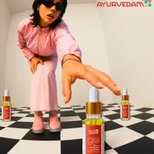 A girl wearing a pink dress, trying to grab the bottle of kumkumadi oil