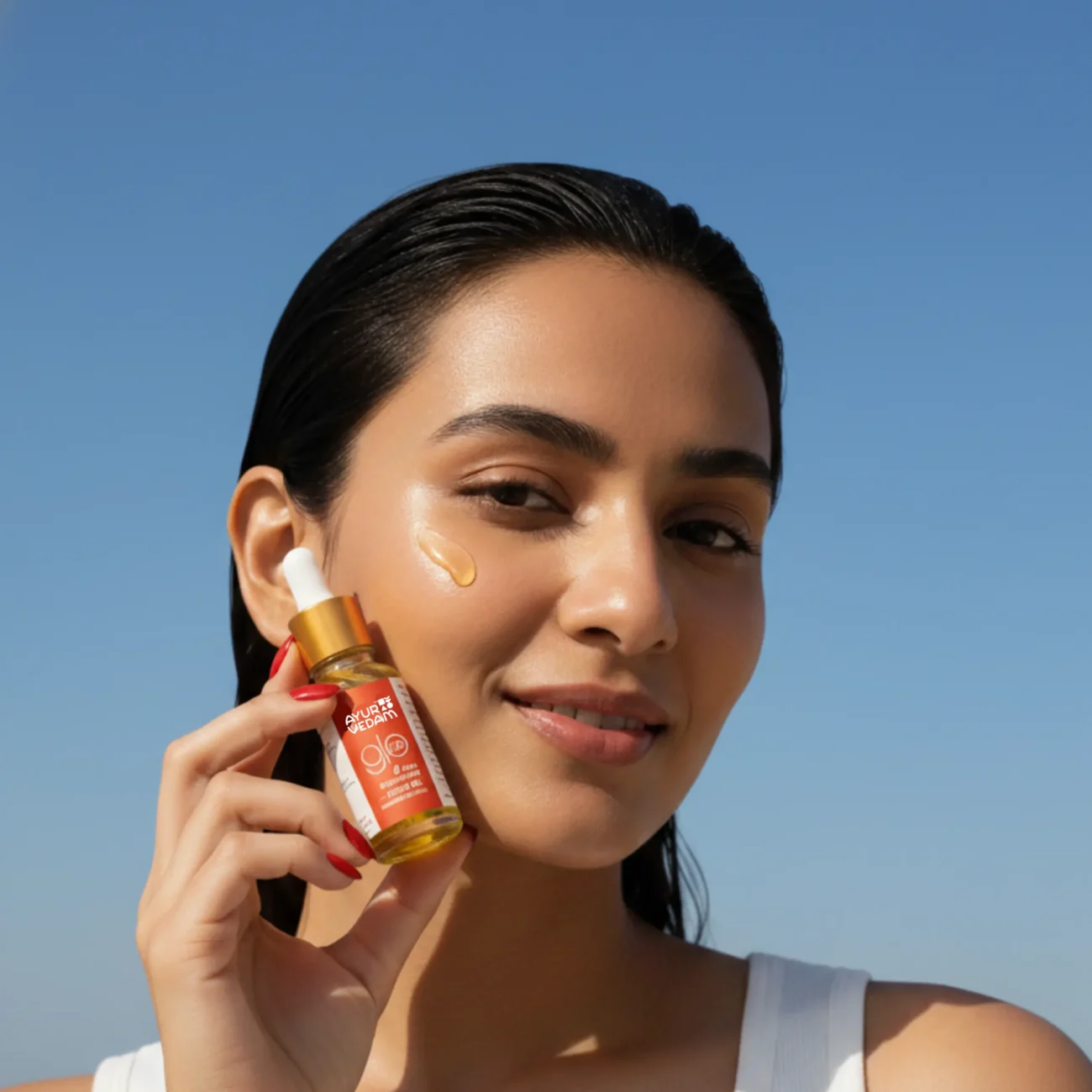 A girl holding a bottle of Kumkumadi Elixir Oil close to her face