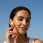 A girl holding a bottle of Kumkumadi Elixir Oil close to her face
