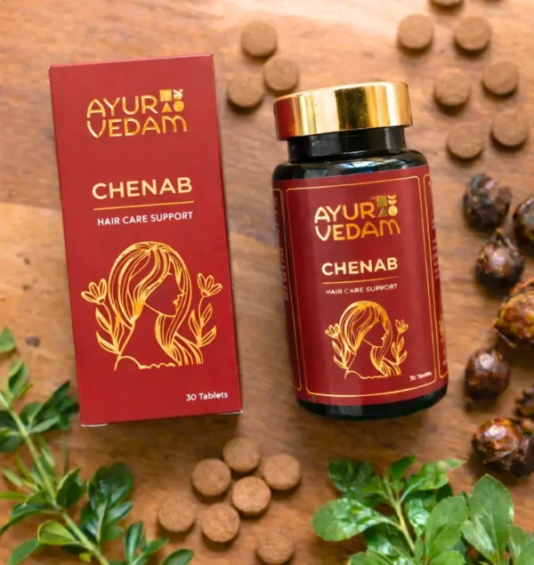Ayurvedam Chenab Ayurvedic hair growth tablets with natural ingredients including Reetha (Soapnuts) and green leaves on a wooden surface.